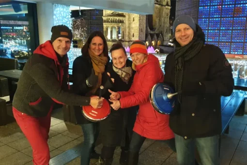 Das Team an den Eisstockbahnen mit der Gedächtniskirche und dem Kurfürstendamm im Hintergrund.